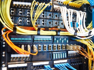 technology equipment with optical fibre cables connected to rack servers in room